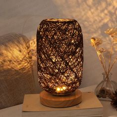 a lamp that is sitting on top of a wooden stand next to a vase with flowers in it