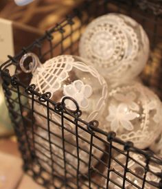 some glass balls in a wire basket on a counter top with a box behind them