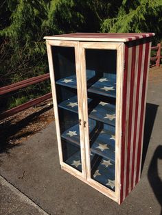 an american flag display case sitting on the side of a road with trees in the background