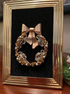 a gold frame with a bow on top of it and some pearls in the middle