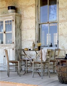 an old wooden table and chairs on a porch