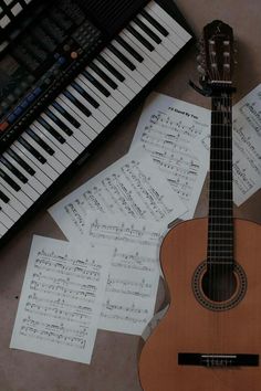 an ukulele sitting on top of sheet music next to a keyboard and piano