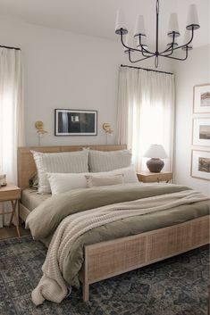 a bedroom with a bed, nightstands and pictures on the wall above it in neutral colors