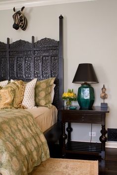 a bedroom with a bed, night stand and lamp on the end table in front of it