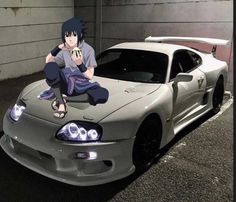 a man sitting on the hood of a sports car in front of a garage door