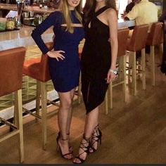 two women standing next to each other at a bar