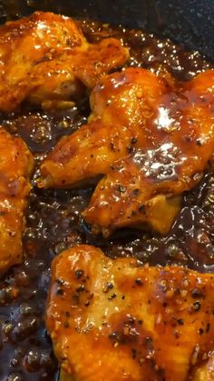 some chicken is cooking in a skillet with brown sauce on the bottom and black pepper sprinkles