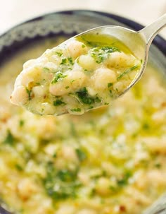 a spoon full of soup with shrimp and broccoli in it, being held up