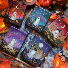 four painted halloween cards with candles and pumpkins in the background