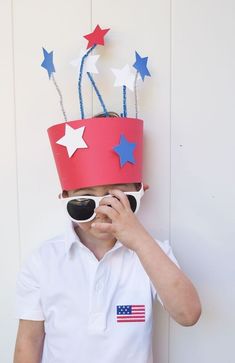 a young boy wearing a red, white and blue paper hat with stars on it