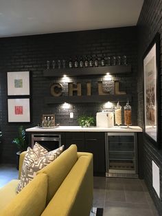 a yellow couch sitting in front of a bar with wine glasses on it's shelves