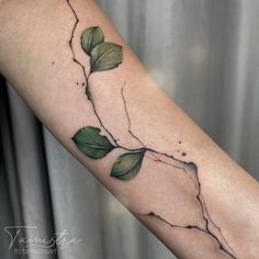 a woman's arm with a vine and leaves tattoo on the left side of her arm