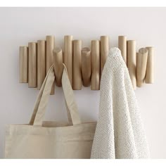 a tote bag hanging on the wall next to a coat rack with wooden pegs