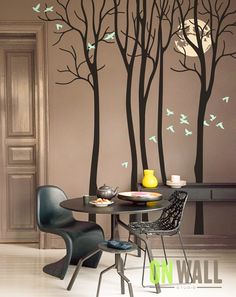 a dining room table with two chairs and a wall decal that has birds flying in the trees