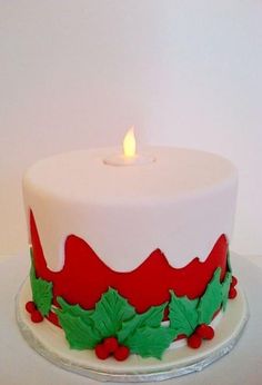 a white and red decorated christmas cake with a lit candle