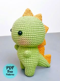 a crocheted green and orange stuffed animal sitting on top of a table next to a white wall