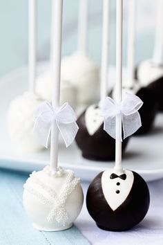 wedding cake pops on a plate with white and black candy bars in the background,