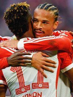 two soccer players are hugging each other in the middle of a hug while wearing red and white uniforms