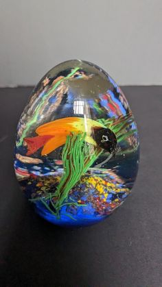 a colorful glass vase sitting on top of a black table next to a white wall