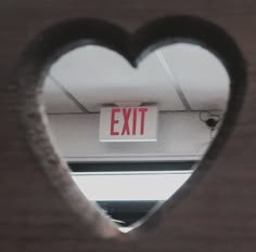 a heart shaped window with an exit sign in it