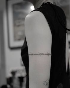 a woman's arm with barbed wire tattoo on the back of her left arm