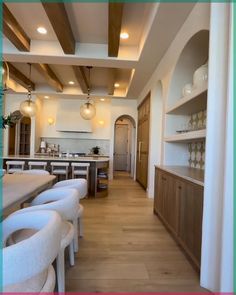 an empty kitchen with white chairs and wood flooring