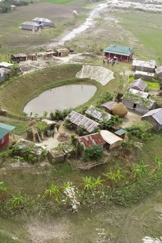 an aerial view of a small village in the middle of a field with water and houses