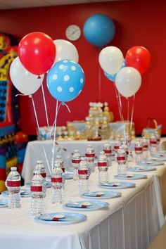 a table topped with lots of red, white and blue balloons