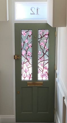 a green door with pink flowers painted on it and the number 12 in front of it