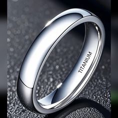 a white gold wedding ring with the name tiffany on it, sitting on a shiny surface