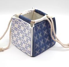 a blue and white bag with rope handles on the front, sitting on a white surface