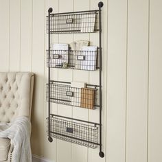 a wall mounted shelf with wire baskets on it next to a chair in a room