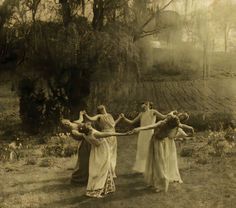 four women in long dresses are holding hands