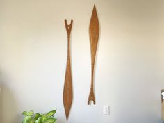 two decorative wooden objects are hanging on the wall next to a potted green plant