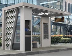 a bus stop sitting on the side of a road next to a tall glass building