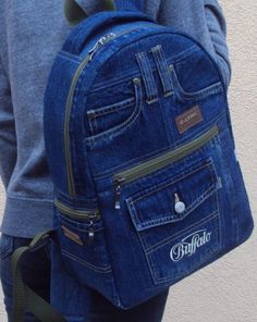 a person wearing a blue jean backpack with zippers on the front and side pockets