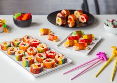 sushi and rainbow colored chopsticks on a white table with bowls of candy