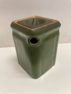 a green vase sitting on top of a white table