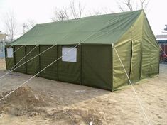 a green tent sitting on top of a dirt field next to a pile of dirt