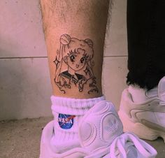 a tattoo on the leg of a person with a white tennis shoe next to it