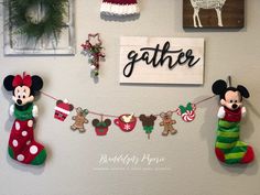 mickey and minnie mouse christmas stockings hanging on the wall in front of a sign that says gather