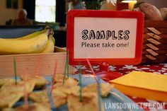 there is a sign that says samples please take one next to some bananas and other snacks