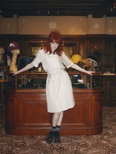 a woman standing in front of a counter with her arms out and hands outstretched to the side