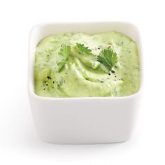 a white bowl filled with guacamole and garnished with cilantro