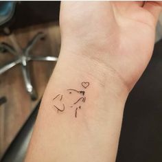 a small tattoo on the wrist of a woman's arm with a dog and heart