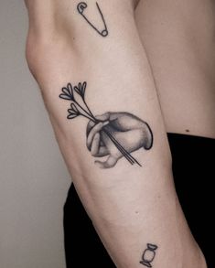 a woman's arm with an arrow and flower tattoo on the left side of her arm