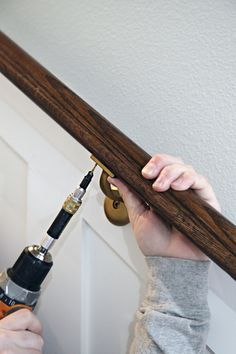 a person using a drill to fix a door handle on a wooden frame with a screwdriver