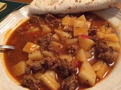 a white plate topped with meat and potatoes covered in gravy next to a burrito