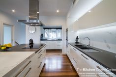 a modern kitchen with white cabinets and black counter tops, stainless steel appliances and wood flooring