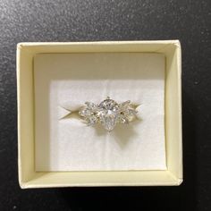 a three stone ring in a white box on a black table with the lid open